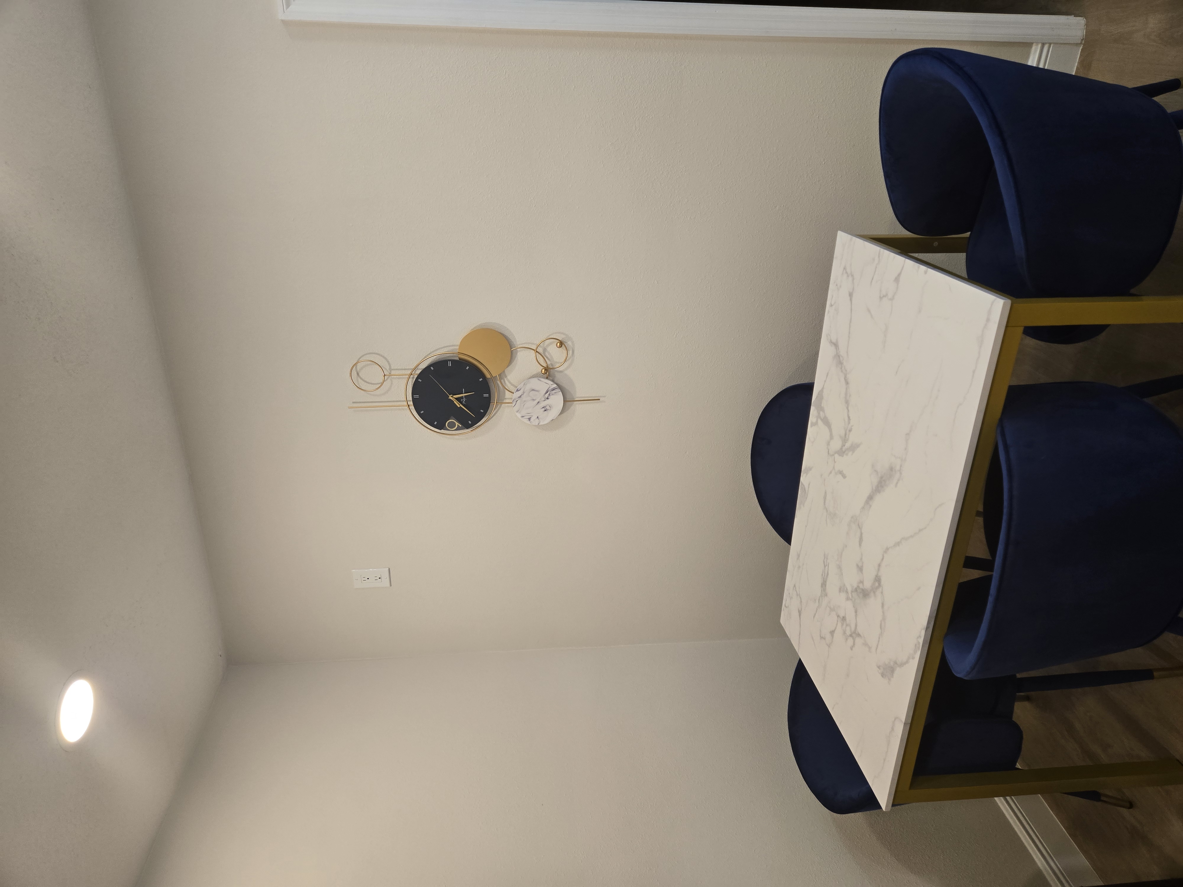 Dining nook with marble table, navy chairs, and statement lighting